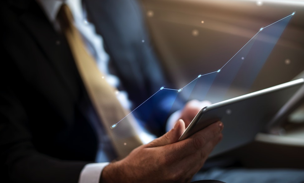 man in suit holding tablet with floating statistics